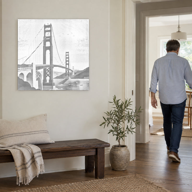 Prikmaleriet “Golden Gate Bridge”, på en lys væg med en person på vej gennem døren ved siden af.