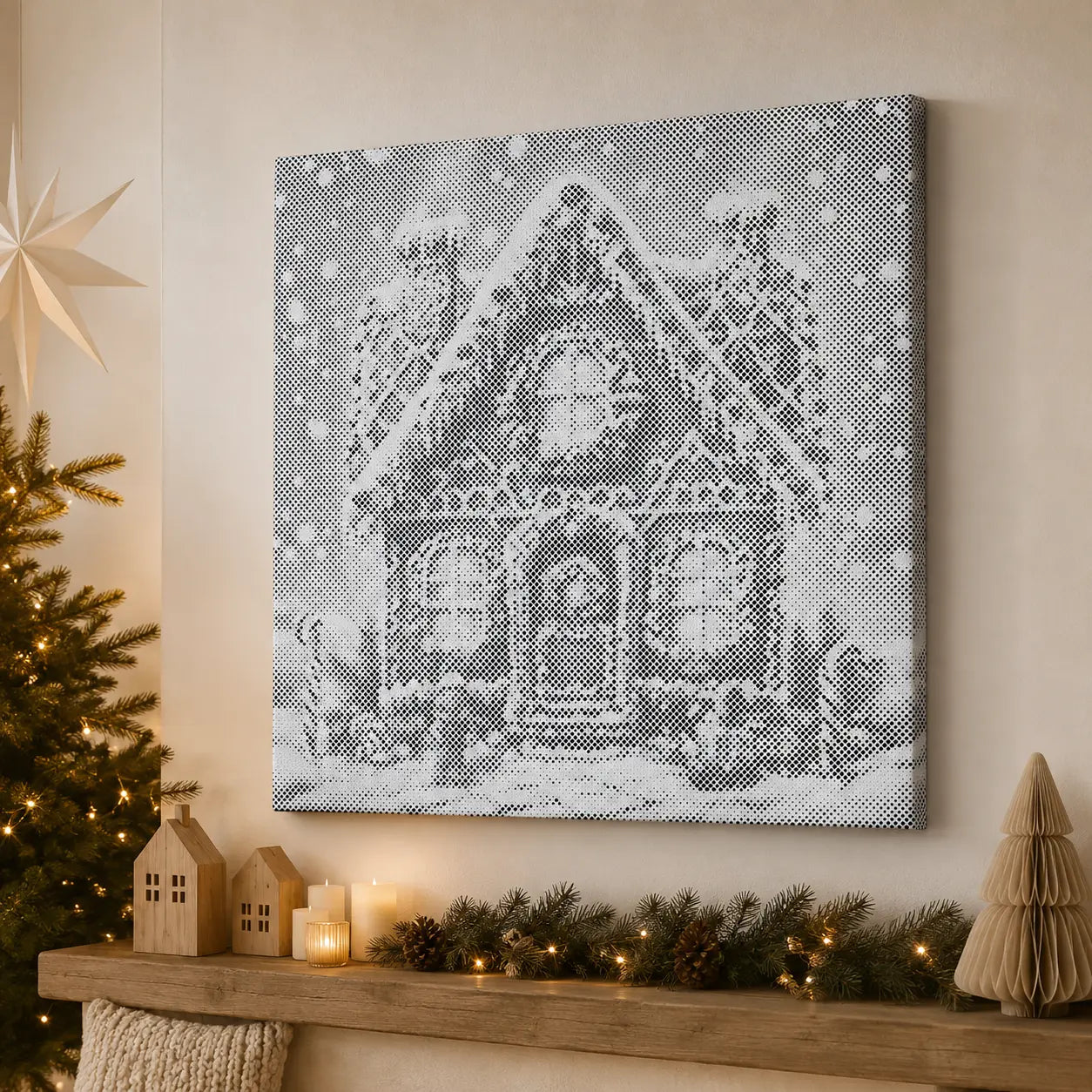 A square canvas wall art print showing a snowy house in black-and-white pixelated style, displayed above a wooden mantel with holiday decor including a lit candle, pinecones, a small paper tree, and a star ornament.