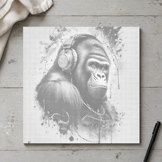 Prikmaleriet “Gorilla med høretelefoner”, set ovenfra på et arbejdsbord i blødt dagslys.