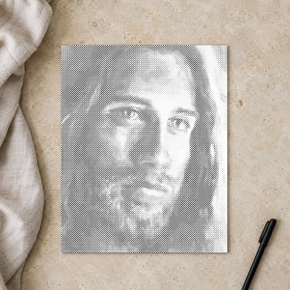 Prikmaleriet “Jesus Kristus”, set ovenfra på et arbejdsbord i blødt dagslys.